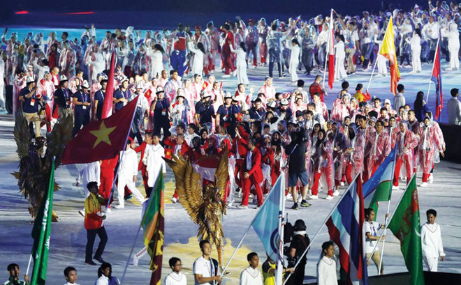 Tình nguyện viên nước chủ nhà rước quốc kỳ Việt Nam tiến vào sân VĐV Bung Karno trong lễ bế mạc Asiad 2018