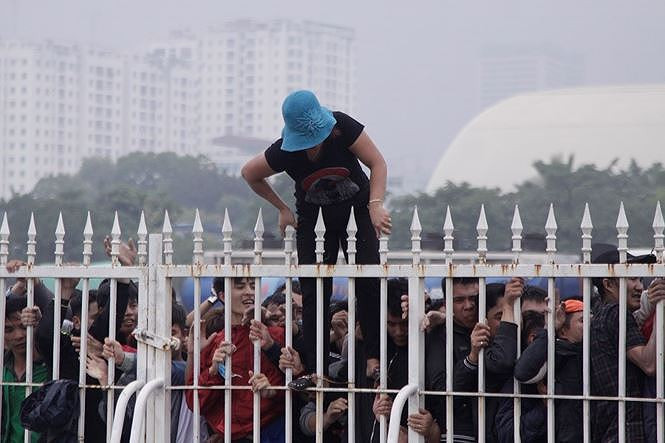 Bất chấp hiểm nguy, một người dân trèo qua hàng rào... Ảnh: TPO