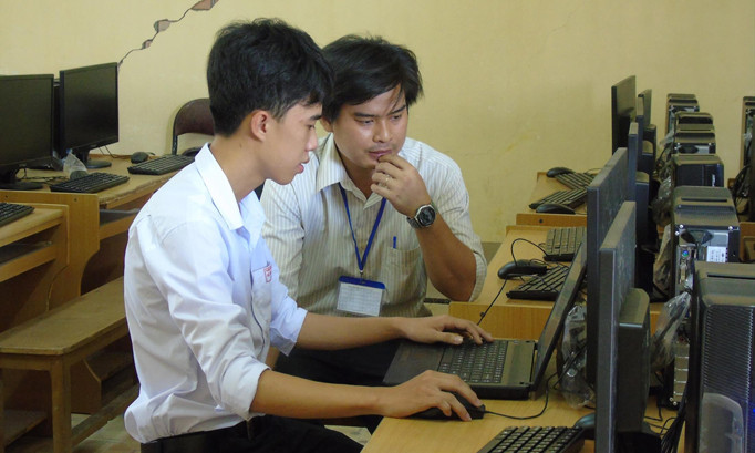 Em Phú được thầy Hưng hướng dẫn lập trình phần mềm. Ảnh: Kim Hà.