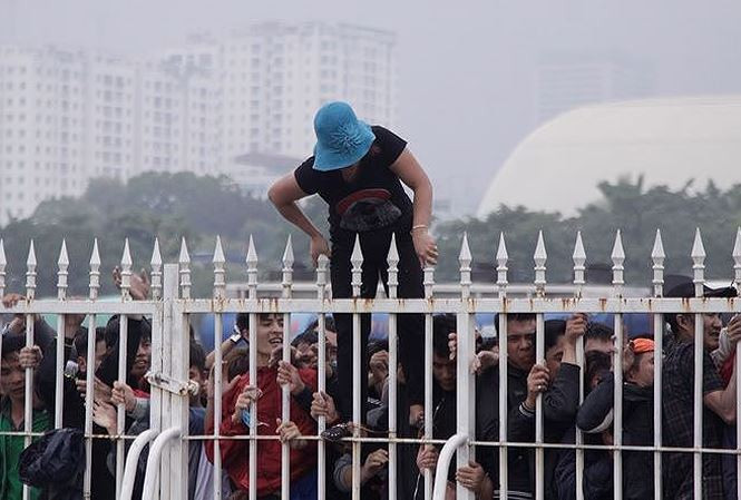 Một CĐV bám chặt hàng rào mong tới lượt mua được vé bóng đá. Ảnh: VSI