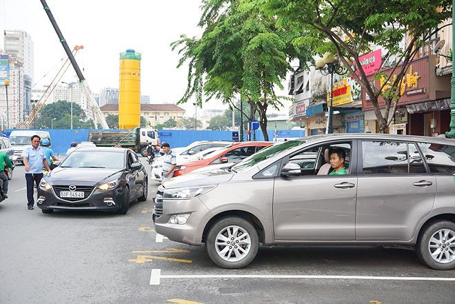 Nhân viên đô thị hướng dẫn tài xế cho xe vào bãi đỗ có thu phí