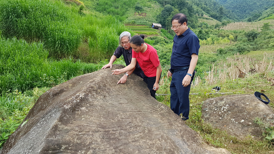 Bí thư xã Đoàn Lao Chải, Lý Thị Thiêm (đứng giữa) thuyết minh về tảng đá cổ cho các vị khách. Ảnh: Xuân Ba 