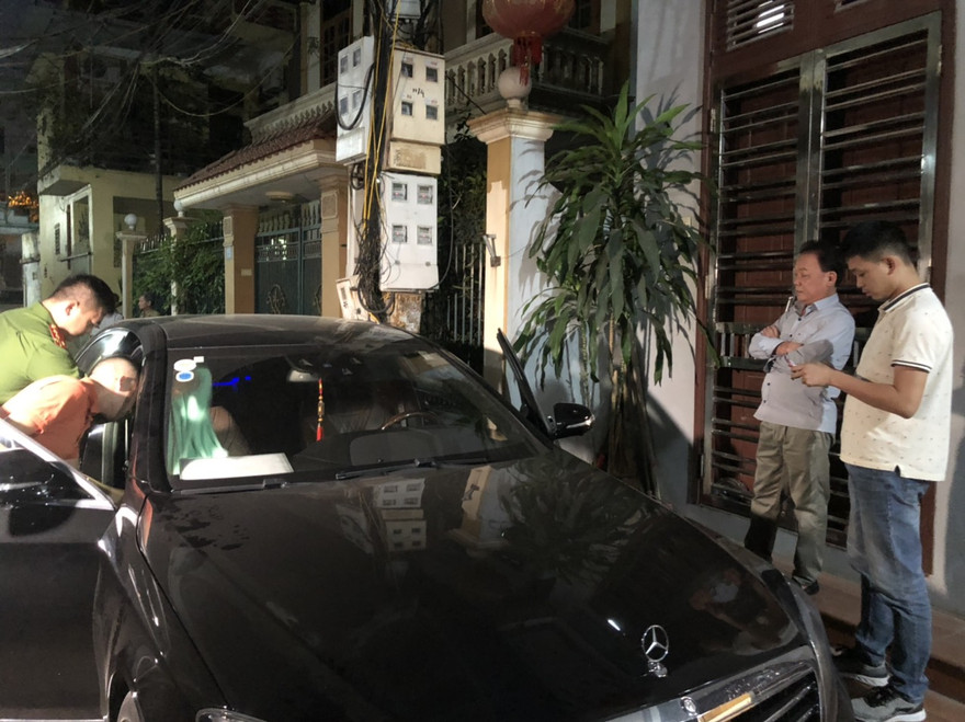 Chúc "Nhị" đứng khoanh tay chứng kiến cơ quan điều tra khám xét xe ô tô của mình (ảnh lớn); Khám xét nhà riêng Chúc “Nhị” (ảnh nhỏ)ảnh: Hoàng Long 