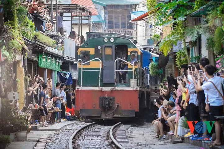 Du khách bất chấp nguy hiểm chụp ảnh tàu chạy qua khu cà phê đường tàu Ảnh: VOV