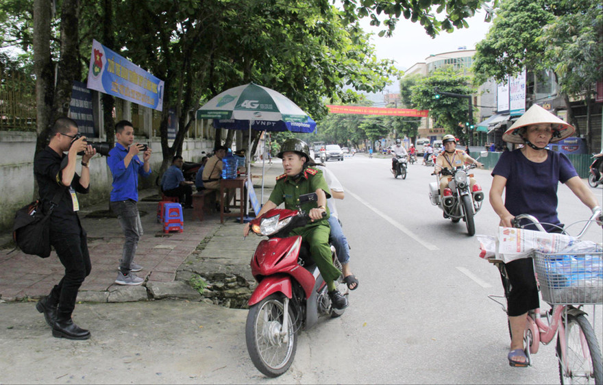 Đại úy Vũ Đức Lợi chở thí sinh Trần Thị Yến đến điểm thi, phía sau có xe chuyên dụng của CSGT hú còi hộ tống Ảnh: Trường Phong 