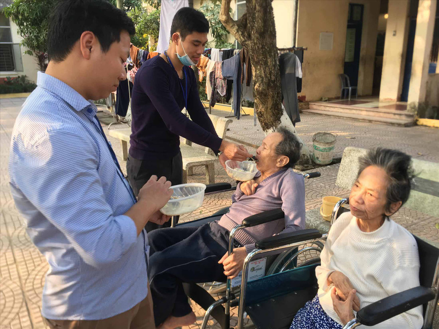 Các cụ cao tuổi được nhân viên Trung tâm hỗ trợ ăn cơm chiều 28/1. Ảnh: Trường Phong