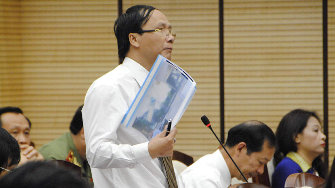 ĐB Nguyễn Hoài Nam (quận Hai Bà Trung) giơ các tấm hình đã chụp về tình trạng thiếu sân chơi cho trẻ em tại phiên chất vấn sáng 7/7. Ảnh: Minh Tuấn.