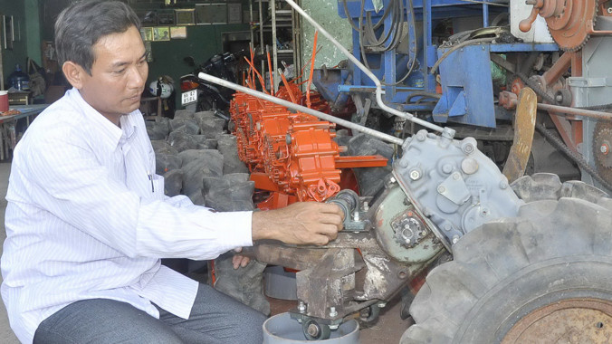 “Kỹ sư chân đất” Phạm Thanh Liêm đang lắp máy. Ảnh: Hòa Hội.