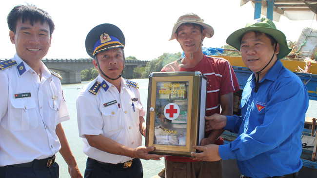 Bí thư T.Ư Đoàn Nguyễn Phi Long và Đại tá Nguyễn Nghiêm Long, Phó Chính ủy Vùng Cảnh sát biển 3 trao tặng hộp thuốc cho ngư dân xã Phước Thuận, chiều 28/3. Ảnh: Nguyễn Minh.