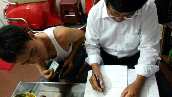 Tổ trưởng khu phố ngõ Chợ Khâm Thiên đang kê khai phí sử dụng đường bộ tại một hộ dân. Ảnh: Như Ý.