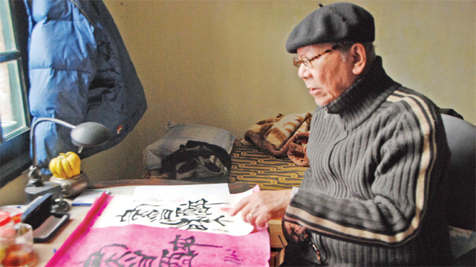 Nhạc sỹ Hoàng Vân bên tác phẩm thư pháp của mình.