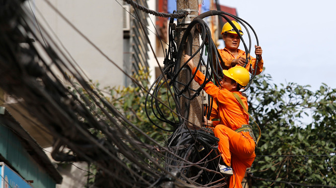 Công nhân Công ty Điện lực đang đấu nối cáp điện trên phố Khâm Thiên - Hà Nội. Ảnh: Ngọc Châu.