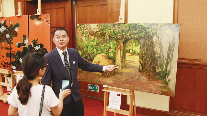Giám tuyển Trần Quốc Hùng giới thiệu về các bức sơn mài sẽ được mang sang Hàn Quốc. Ảnh: N.M.Hà.