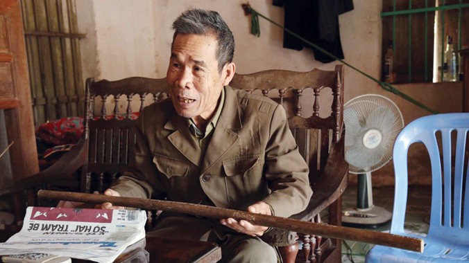 Ông Quán bồi hồi kể lại những kỷ niệm cùng chiếc gậy Trường Sơn. Ảnh: Dương Lê.