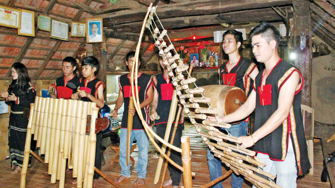 Ban nhạc gia đình Y Thim đang biểu diễn phục vụ khách tham quan trong ngôi nhà dài.