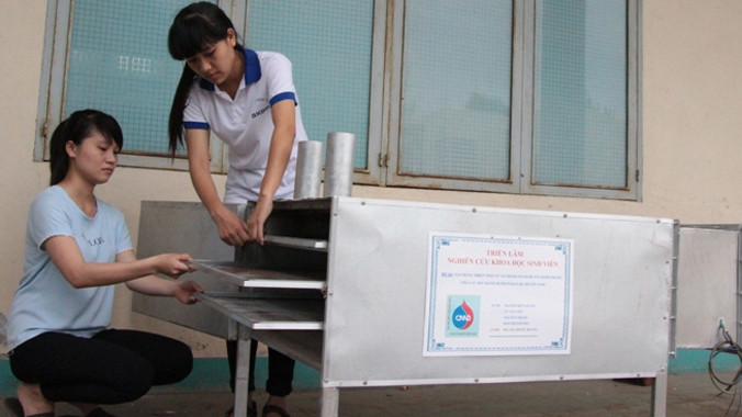 Các bạn sinh viên bên sản phẩm ứng dụng từ nhiệt thải lò bánh tráng để sấy khô bánh. Ảnh: Đào Phan.