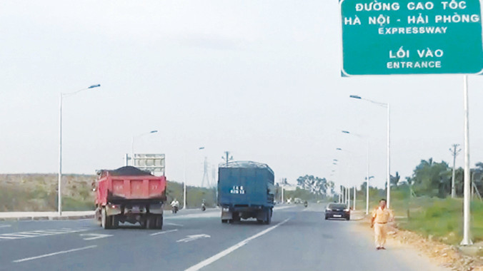 CSGT (bìa phải) đang tiến lại tổ công tác của TTGT, trong khi xe quá tải ngang nhiên đi lại.