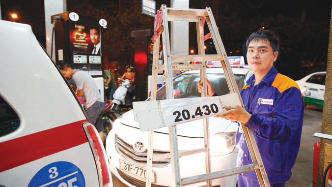 Nhân viên Petrolimex gần đây liên tục phải bắc thang treo biển tăng giá xăng (Ảnh chụp ngày 20/5). Ảnh: Hồng Vĩnh.