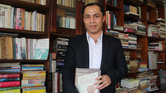 Anh Tuấn bên tủ sách của mình. Ảnh: Thanh Trần.