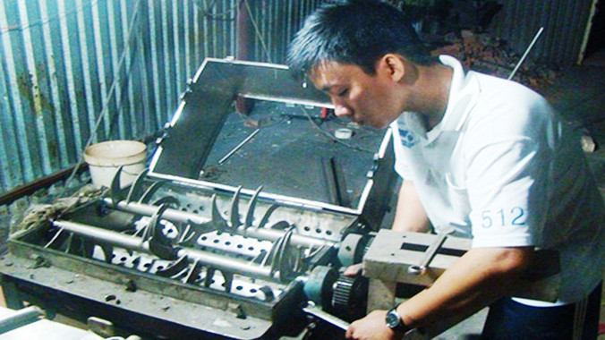 Võ Đông Phú đang bảo trì chiếc máy tán bột.