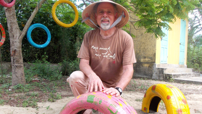 Cựu binh Mỹ bên những chiếc bánh xe sơn màu đã hoàn thành. Ảnh: Nguyễn Trang.