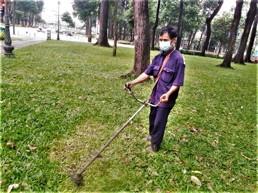 Anh Nghĩa miệt mài cắt cỏ trong công viên trước dinh Độc Lập trong ngày giãn cách