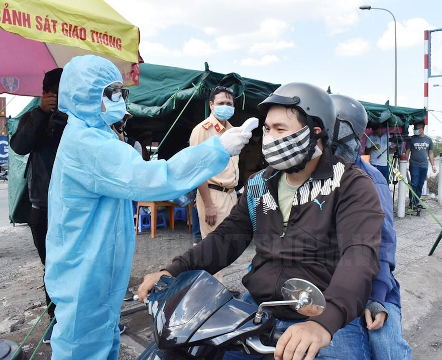 Lực lượng chức năng đo thân nhiệt người vào TPHCM tại chốt kiểm dịch phòng, chống dịch COVID-19 trên quốc lộ 1A Ảnh: Hcmcpv.org.vn