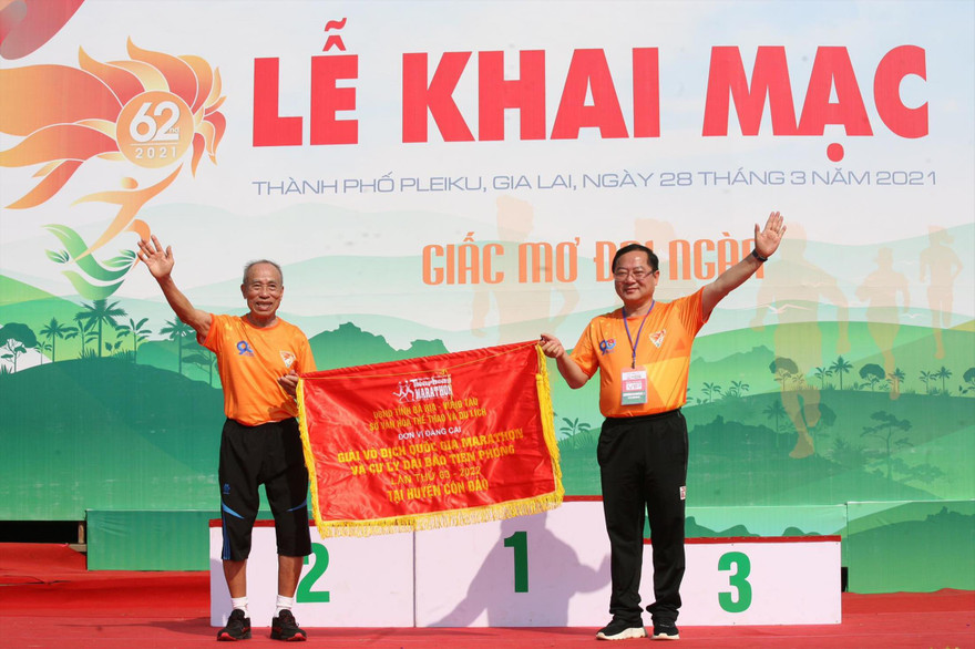 HLV Bùi Lương thay mặt Bà Rịa-Vũng Tàu nhận cờ đăng cai Tiền Phong Marathon 2022 tổ chức tại Côn Đảo từ nhà báo Lê Xuân Sơn, Tổng biên tập báo Tiền Phong, trưởng BTC giải. Ảnh: Như Ý 