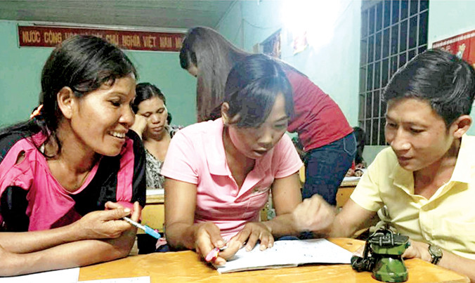 Thầy cô hướng dẫn chị em viết chữ.