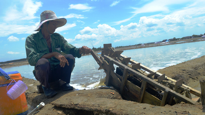 Anh Tòng lấy nước vào ruộng muối giữa 12 giờ trưa nắng. Ảnh: Ngô Bình