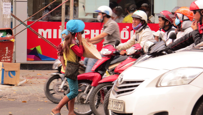 Bồng bế trẻ nhỏ chặn đầu ô tô xin tiền. Ảnh: Ngô Bình