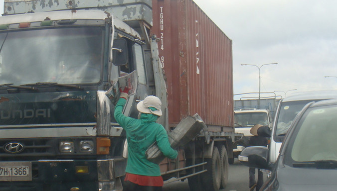 Người bán hàng rong lọt thỏm giữa dòng xe cộ qua lại trên quốc lộ thuộc địa bàn quận Thủ Đức.