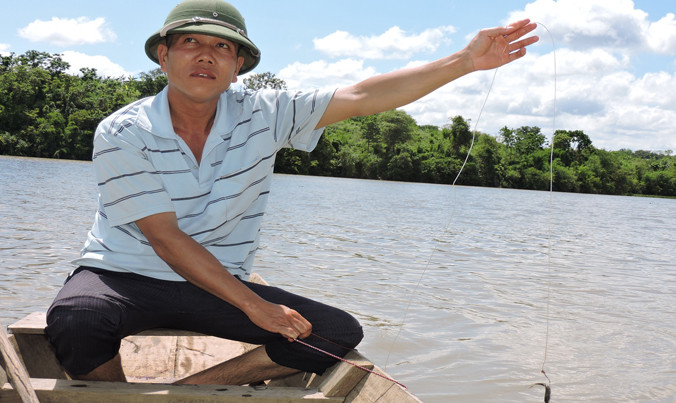 Ngư phủ Cảnh kiểm tra mồi câu trên sông.