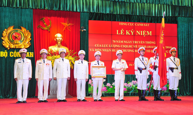 Lãnh đạo Bộ Công an tặng bằng khen và gắn huy chương lên cờ của lực lượng Cảnh sát QLHC và TTXH. Ảnh: Xuân Ân