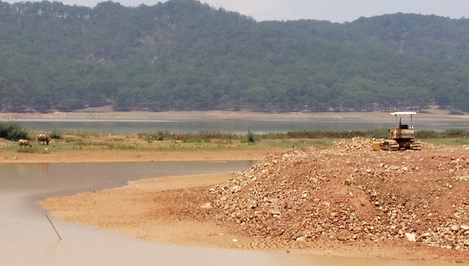 Dùng xe cơ giới san gạt đất xuống hồ để lập vườn.