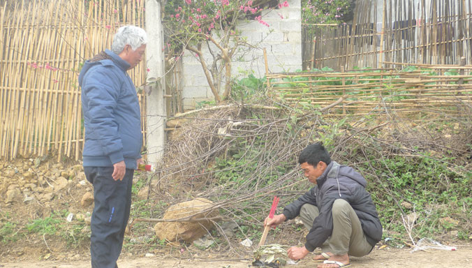 Bác sỹ Đại (bìa trái) và người dân làng Khuổi Mươi thắp nhang tưởng nhớ đến các chiến sỹ áo trắng đã hy sinh vì quê hương (ảnh chụp chiều ngày 16/2/2016). Ảnh: Duy Chiến