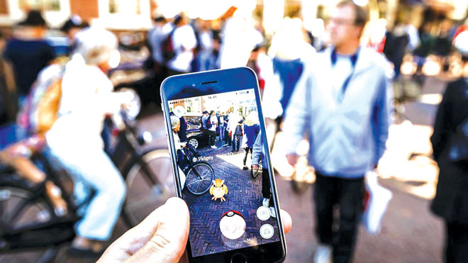 Màn hình người chơi Pokemon Go hiển thị hình ảnh thực không gian xung quanh và nhân vật hoạt hình trên đó để họ ném bóng ảo bắt con vật. Ảnh: Independent