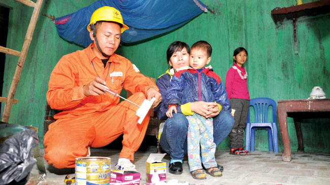 Nhân viên ngành điện sửa chữa điện miễn phí cho một hộ nghèo.