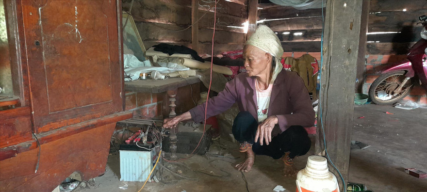 Bà Chìu Thị Tài bên chiếc bình ắc quy cũ kỹ