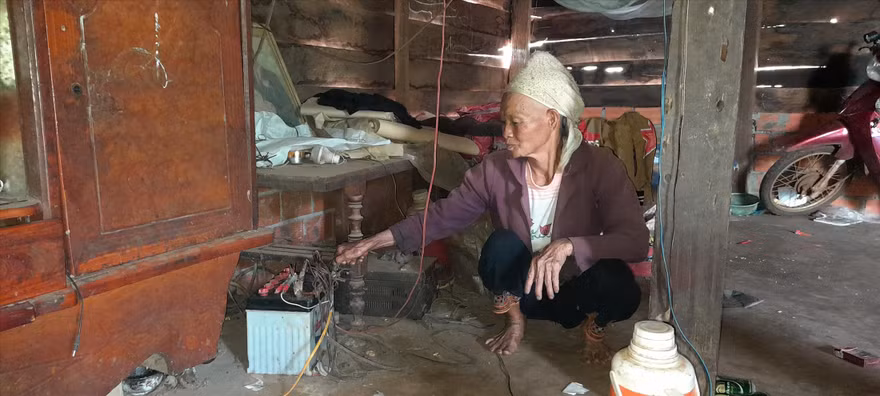 Bà Chìu Thị Tài bên chiếc bình ắc quy cũ kỹ