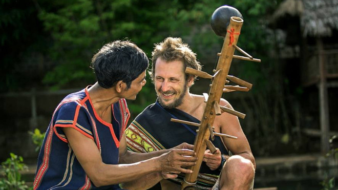 Nghệ nhân Rơ Châm Tih giới thiệu đàn goong với khách nước ngoài.