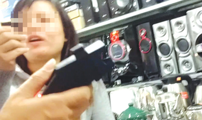 Chủ ki ốt giới thiệu tính năng súng bắn điện, dùi cui điện tại chợ Hạ Long. Ảnh: MĐ