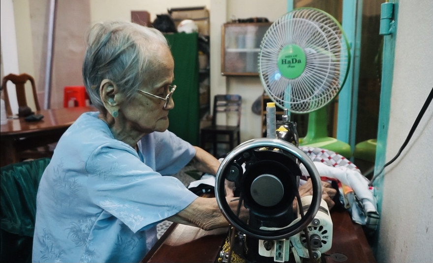 Mẹ Quýt bên chiếc máy may cũ kĩ, theo bà suốt mấy chục năm qua 