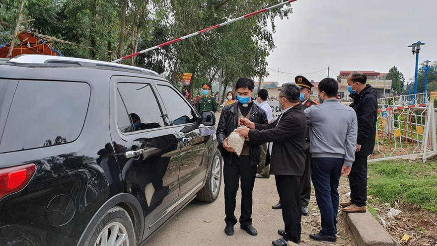 Linh mục Hoàng Trọng Hữu (bìa trái) cầm túi bánh khi vào khu vực tâm dịch. Ảnh: F.X 