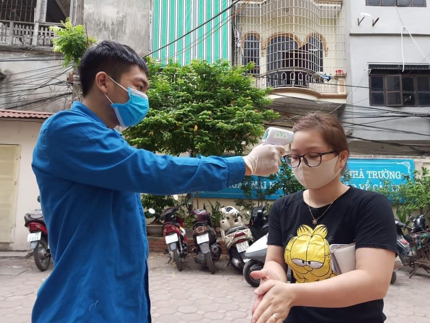Thanh niên tình nguyện quận Đống Đa đo thân nhiệt người dân đến lấy mẫu xét nghiệm. ẢNH: NVCC 