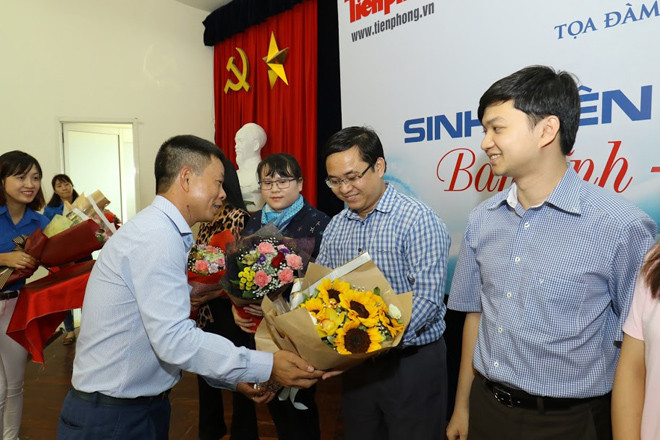 Phó Tổng biên tập Phùng Công Sưởng tặng hoa cho các đại biểu tham gia buổi tọa đàm trực tuyến. Ảnh: Như Ý