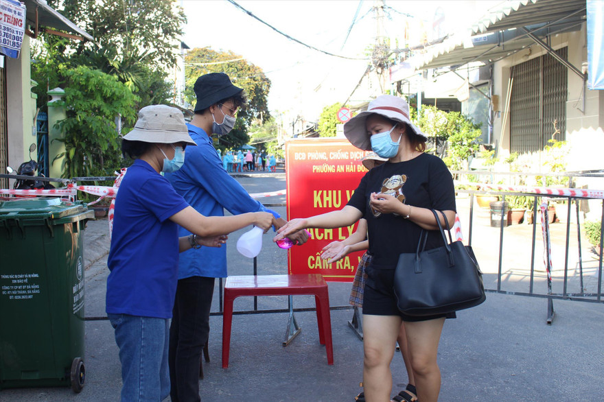 Tình nguyện viên ở chốt phong tỏa “mềm” đường An Dương Vương (quận Ngũ Hành Sơn) hỗ trợ người dân ra vào khu cách ly. - Ảnh: Giang Thanh