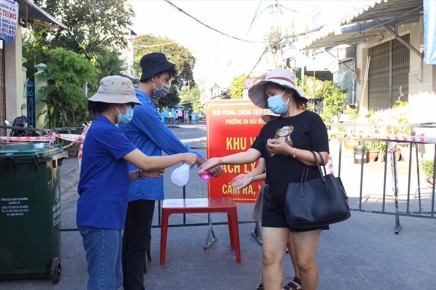 Tình nguyện viên ở chốt phong tỏa “mềm” đường An Dương Vương (quận Ngũ Hành Sơn) hỗ trợ người dân ra vào khu cách ly. - Ảnh: Giang Thanh