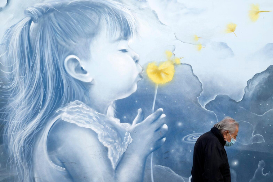 Một cụ ông đeo khẩu trang đi qua bức tranh tường ở nhà ga Athens (Hy Lạp) ngày 15/11. Ảnh: AP 