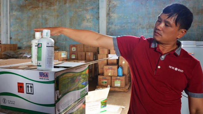 Thủ kho chi nhánh Cty Thuận Phong lấy chai phân bón ra khỏi thùng để đoàn kiểm tra. Ảnh: HTN.